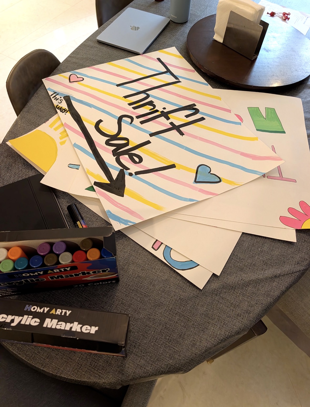 Handmade thrift sale posters being created with colorful markers