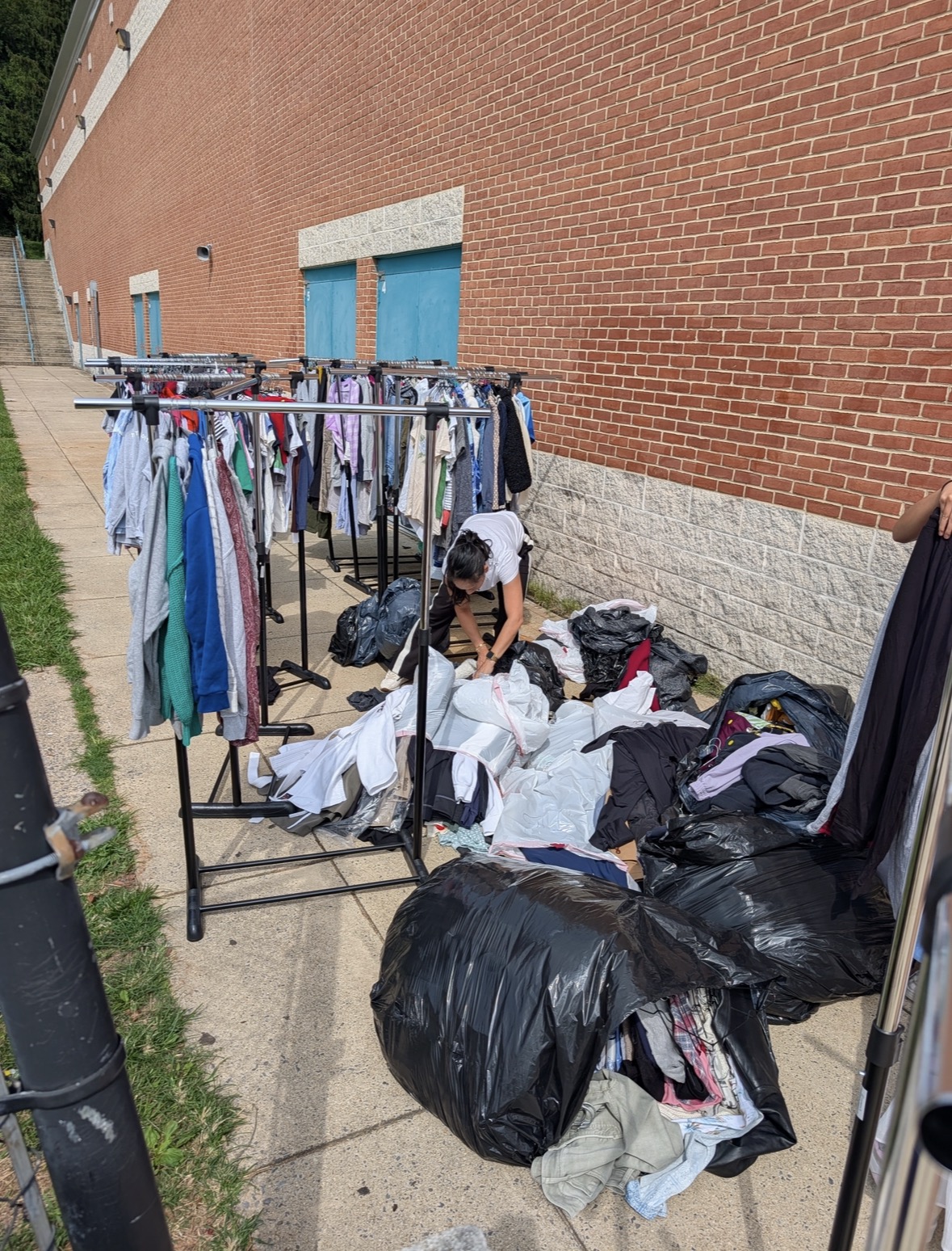 Volunteers sorting clothing outside beside racks before the thrift sale