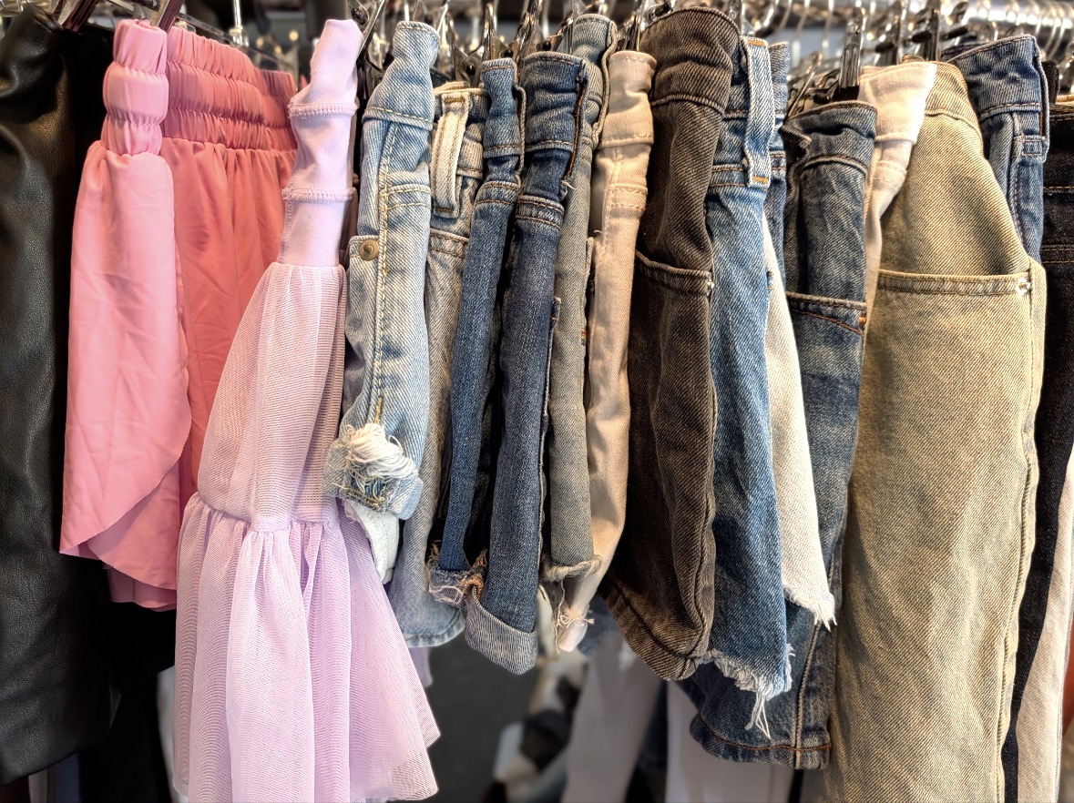 A close-up of colorful clothing and denim hanging on a rack
